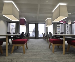 Large white tables with wooden legs. Matching chairs and low stools with wooden legs for office breakout area