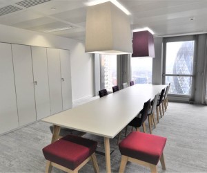 Long meeting table with white top and wooden legs, sits 12 people