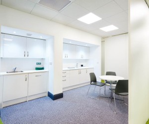 large open plan white office kitchen with breakout table and chairs